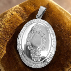 RELICARIO OVALADO 23*30MM C/ RELIEVES AL CENTRO Y BORDE DIJE